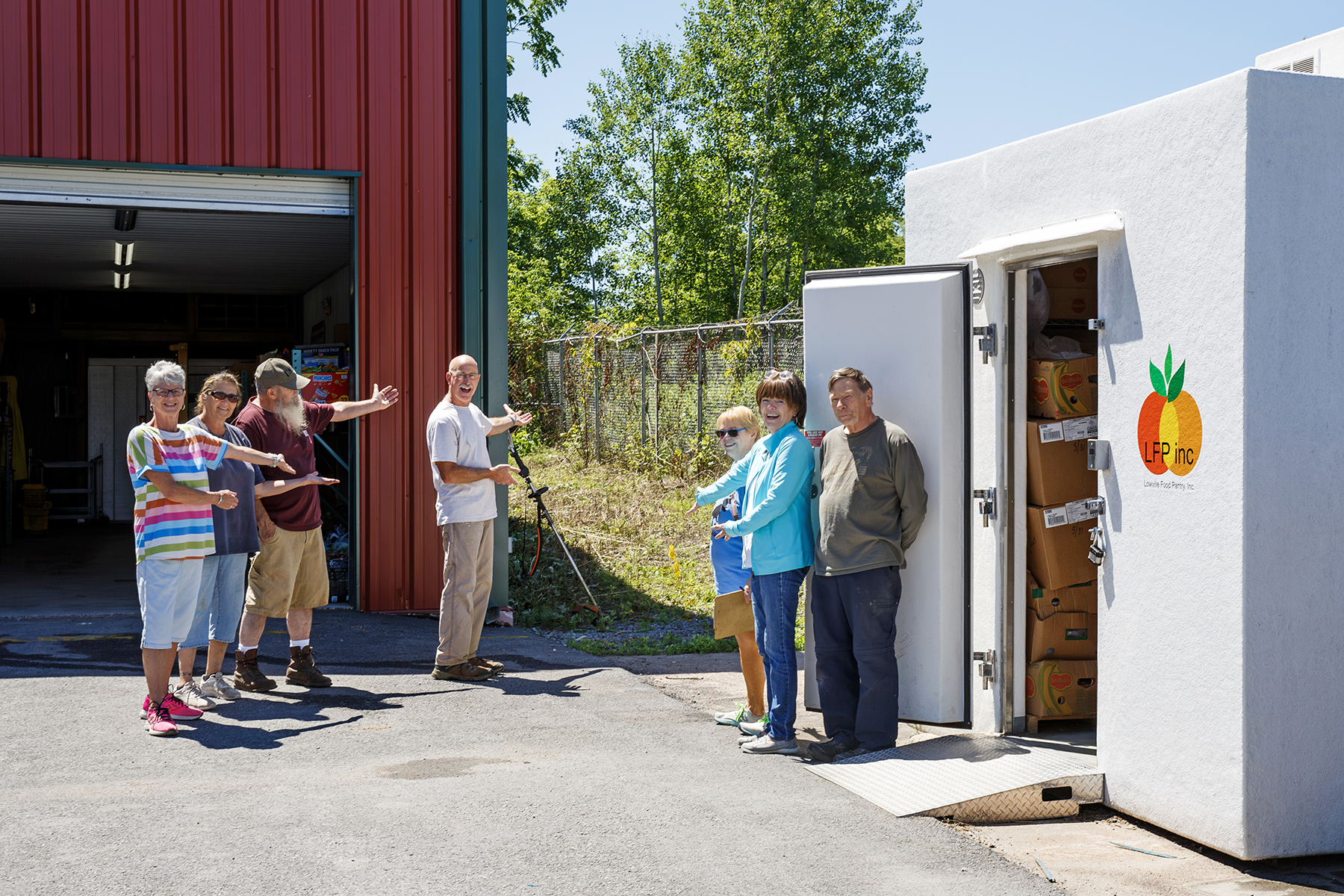 From left, Margaret Everson; Jane Peters; Bob Adams; Mike Hanno; Sara Brooker; Nancy Hanno and Bob Fort show where the new 30 foot long freezer will go next to the loading garage at the Lowville Food Pantry in the village Friday, June 28, 2024. © Kara Dry Photography LLC